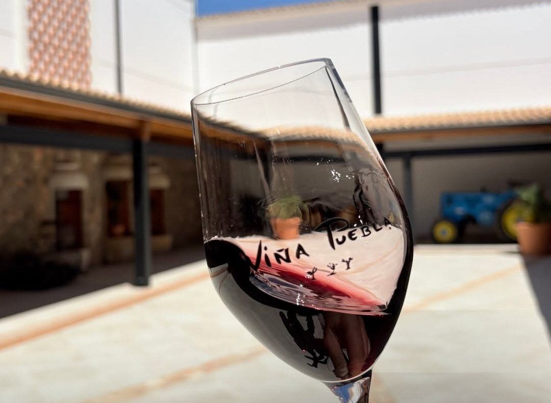 Copa de vino tinto con el logo de Viña Puebla grabado, en el patio de la bodega